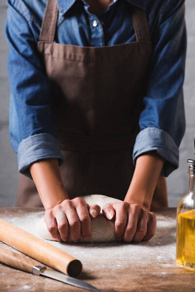 partial view of woman kneading dough for pizza