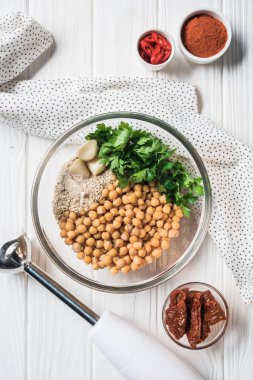 Nohut ve diğer malzemeler için humus kase, blender ve ahşap masa üzerinde kurutulmuş domates ile düz göklere