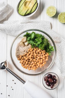 Nohut ve diğer malzemeler için humus kase, blender ve avokado ahşap masa üzerinde düz yatırın
