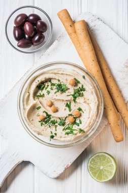 Humus maydanoz, breadsticks, zeytin ve limon ile üstten görünüm ahşap masa üzerinde
