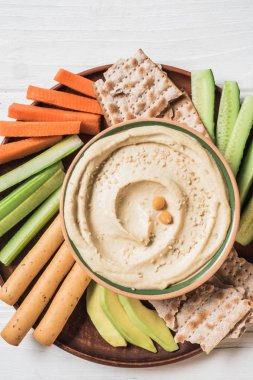 Humus görücü usulü kesilmiş sebzeler kase üstten görünüm dilim, ahşap yüzeyde breadsticks ve pide ekmek