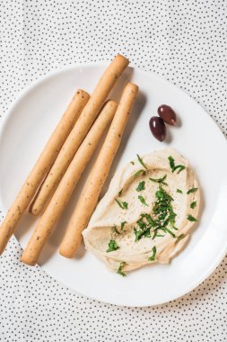 keten plaka üzerinde Humus, breadsticks ve zeytin üstten görünüm