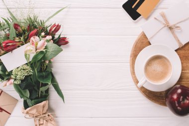 düz lay kaydırılan buket çiçek, fincan kahve ve beyaz ahşap masa üzerinde kredi kartı ile