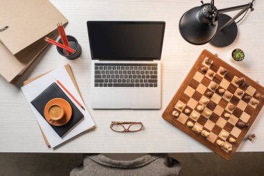 çalışma alanı gözlük, kahve fincanı, satranç tahtası ve dizüstü bilgisayar ile yükseltilmiş görünümü tablo