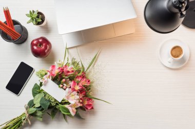 çalışma alanı tebrik kartı çiçekler, dizüstü bilgisayar, kahve ve smartphone ile üstten görünüm tablo