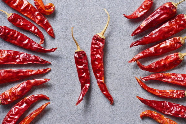 top view of red chili peppers arranged on grey tabletop