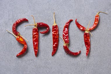 top view of dried chili peppers arranged in spicy lettering on grey tabletop clipart