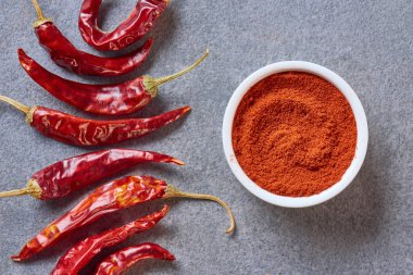 top view of arranged grinded and wholesome chili peppers on grey tabletop clipart