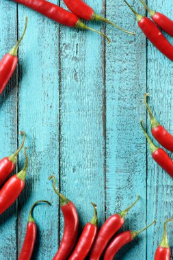 top view of red ripe chili peppers on blue wooden table clipart