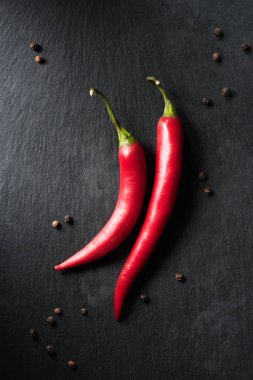 top view of two ripe chili peppers on black surface clipart