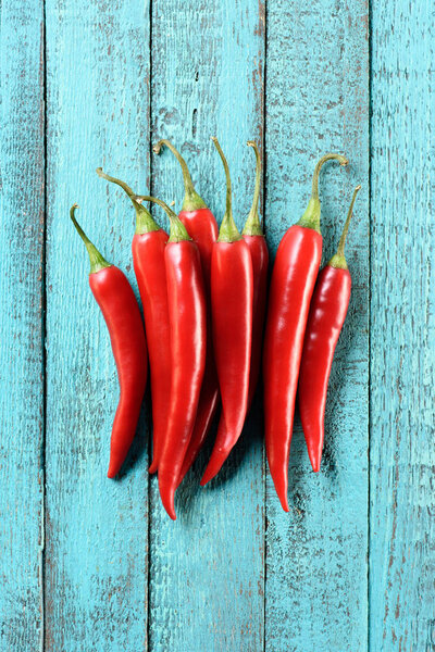 сверху вид на груду красных спелых перцев чили на синем деревянном столе

