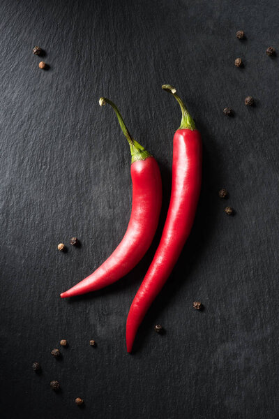 top view of two ripe chili peppers on black surface