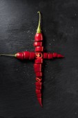 Картина, постер, плакат, фотообои "elevated view of two cut red ripe chili peppers on black surface", артикул 210840570
