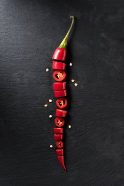 top view of cut red ripe chili pepper on black surface 