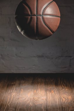 ahşap zemin üzerinde düşen kahverengi basketbol topu