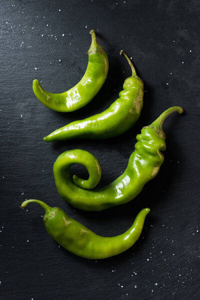 top view of green ripe chili peppers on black surface