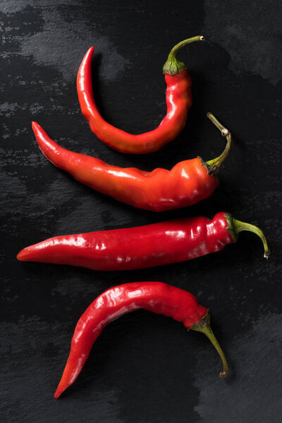 top view of raw red chili peppers on black tabletop