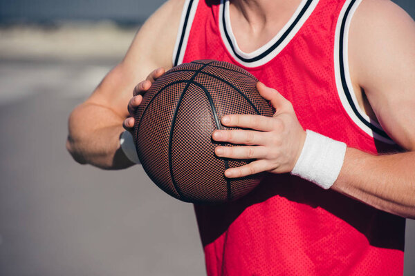 обрезанный образ спортсмена, играющего в баскетбол на улице
