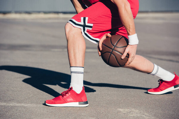 cropped image of basketball player playing basketball on street