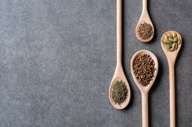 tahta kaşıklar kurutulmuş aromatik baharat ile üstten görünüm gri arka plan üzerinde