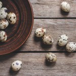Top view of healthy raw quail eggs on plate on wooden table