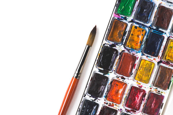 вид кисти и красочные акварельные краски на белом фоне
