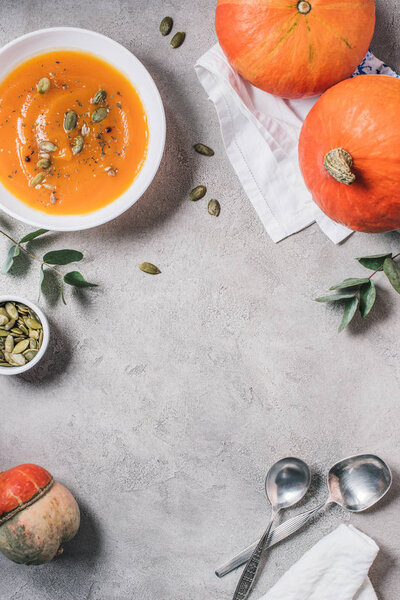 flat lay with pumpkins and plate with pumpkin cream soup on table 