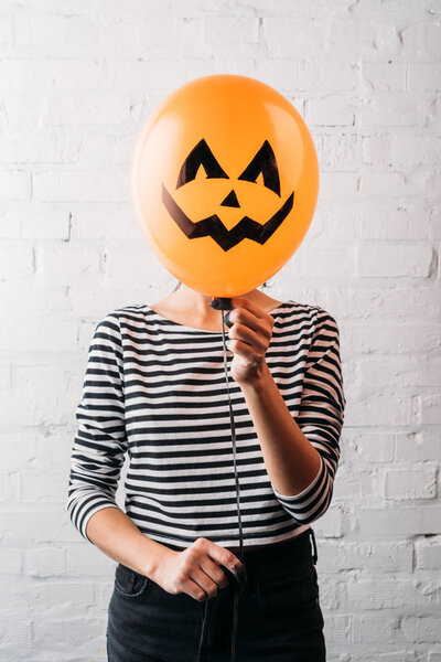 woman holding halloween balloon in front of head