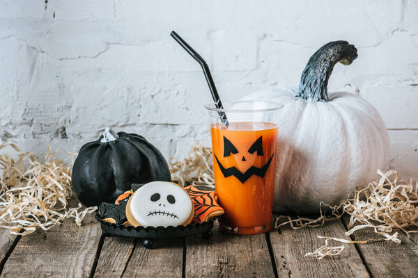 close-up shot of halloween composition with pumpkins, cookies and glass of pumpkin juice