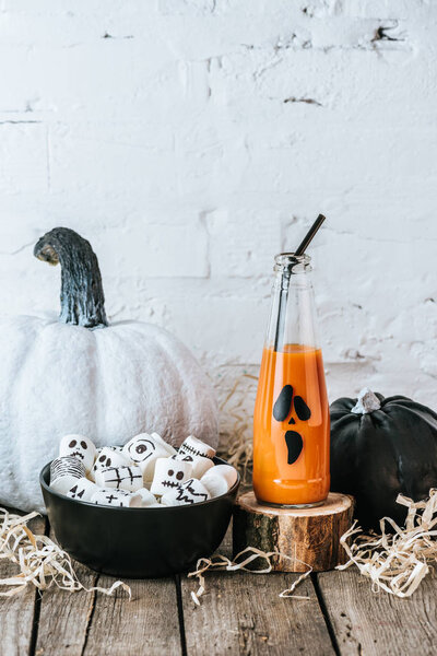 close-up shot of halloween composition with pumpkins, marshmallows and bottle of pumpkin juice