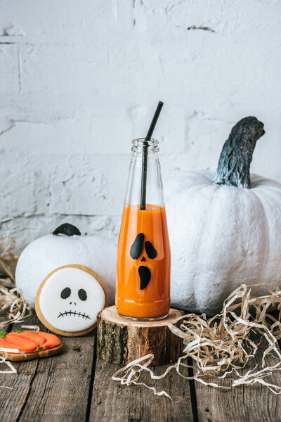 close-up shot of halloween composition with pumpkins, cookies and bottle of pumpkin juice