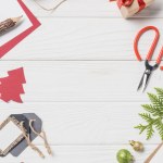 Flat lay with arranged christmas present, baubles and evergreen branches on wooden table