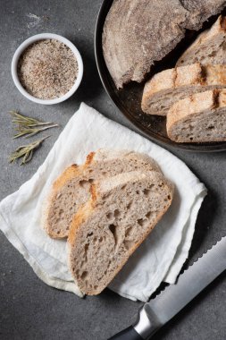 düz lay kesme somun ekmek, bıçak ve gri masa üzerinde beyaz keten ile