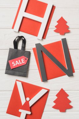 happy new year ve alışveriş çantası ahşap masa üzerinde Satılık işareti olan yazı, üstten görünüm