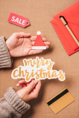 kredi kartı ve satış ile yüzey üzerinde neşeli Noel yazı ve santa şapka tutan kadın kırpılmış görüntü 