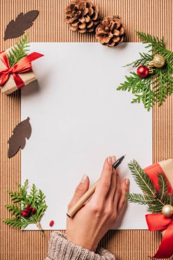 kalem ile yüzeyde kadınla kırpılmış görüntü kağıt boş ve Noel hediye kutuları baubles ve evergreen dalları ile dekore edilmiş