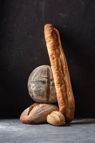 close up view of loafs of ciabatta and baguette on black background