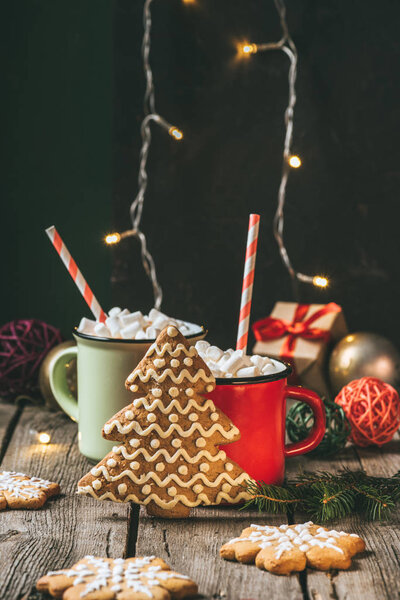 two cups of christmas cocoa with marshmallows and gingerbread christmas tree