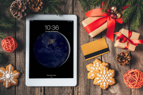вид планшета ipad, кредитная карта, пряничное печенье и рождественские подарки на деревянном фоне
