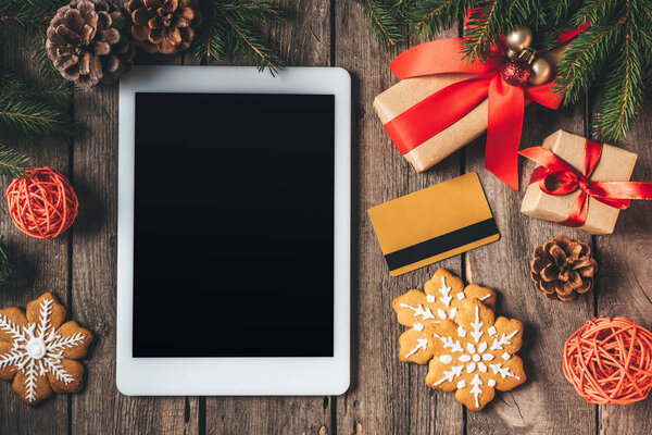 квартира лежать с цифровой планшет, кредитная карта, печенье и рождественские подарки на деревянном фоне
