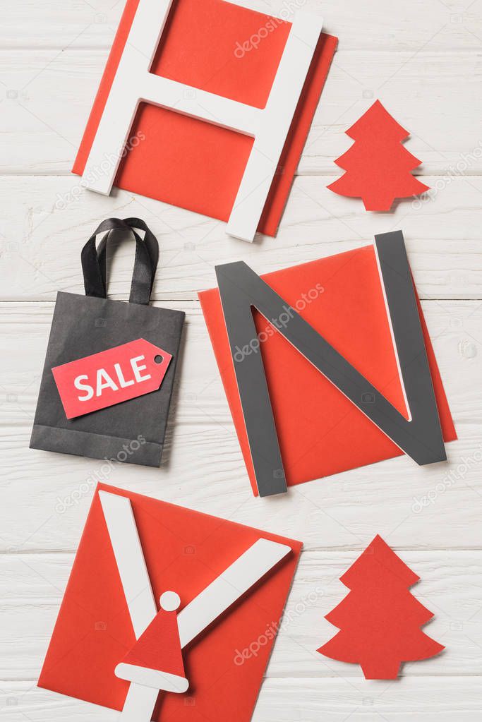 top view of lettering happy new year and shopping bag with sale sign on wooden table