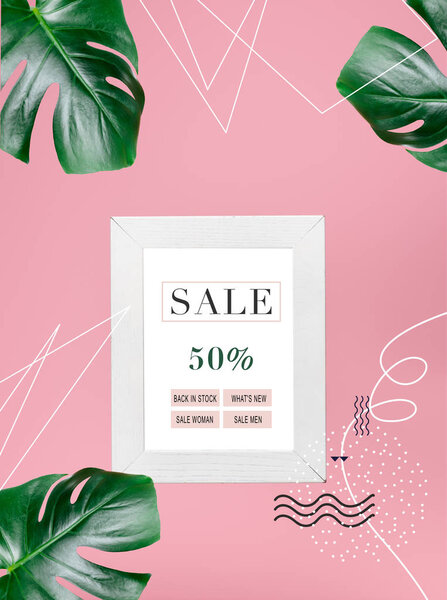shopping blackboard with 50 percents sale isolated on pink with tropical monstera leaves