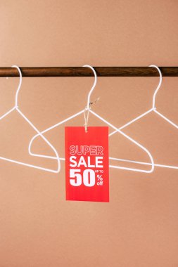 hangers with red super sale tag - 50 percents discount for black friday shopping on beige clipart