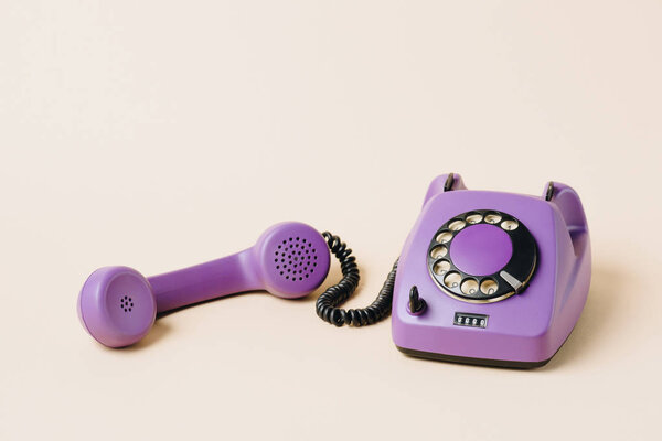purple retro rotary phone with tube on beige