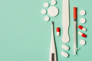 yeşil zemin üzerine, ilaç, elektronik termometre ve şırınga üstten görünüm