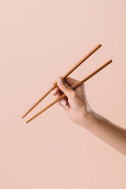 cropped shot of woman holding chopsticks isolated on beige clipart