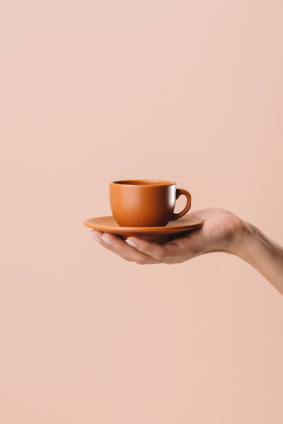 cropped shot of woman holding cup of coffee isolated on beige