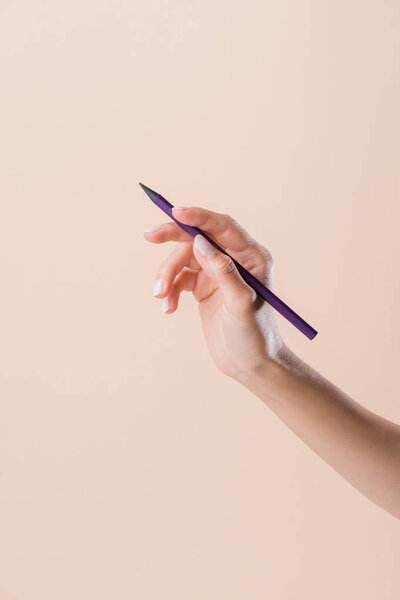 cropped shot of woman holding purple pencil isolated on beige