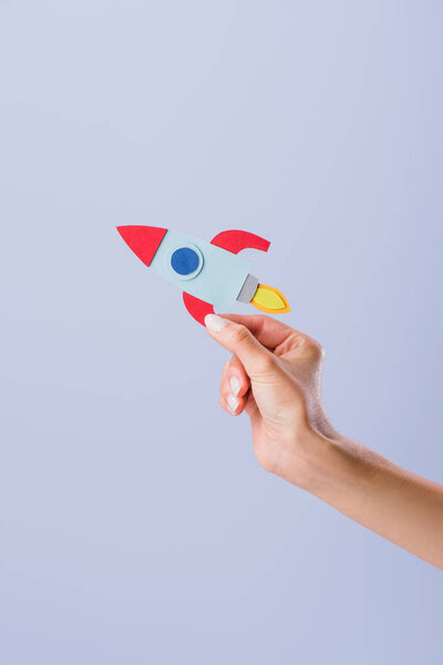 cropped shot of woman holding cardboard rocket isolated on purple