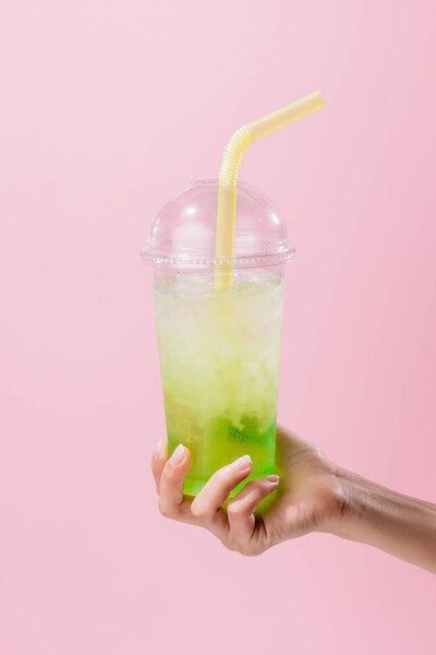 cropped shot of woman holding plastic cup of mojito isolated on pink